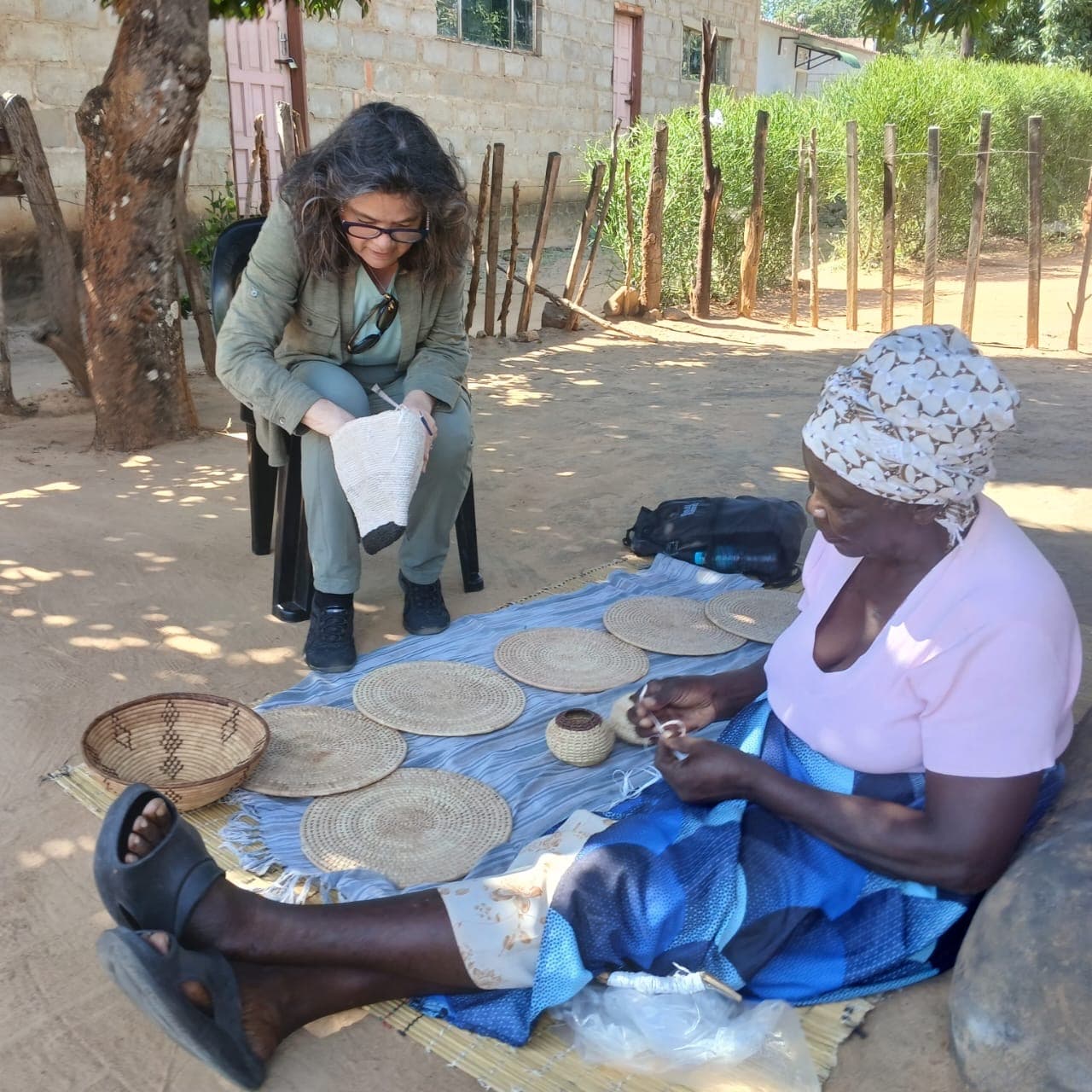 A basket maker sharing her work with a visitor