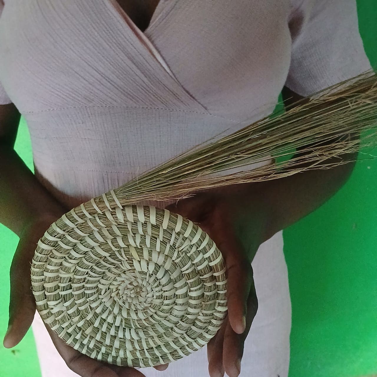Hands holding a woven basket and weaving materials