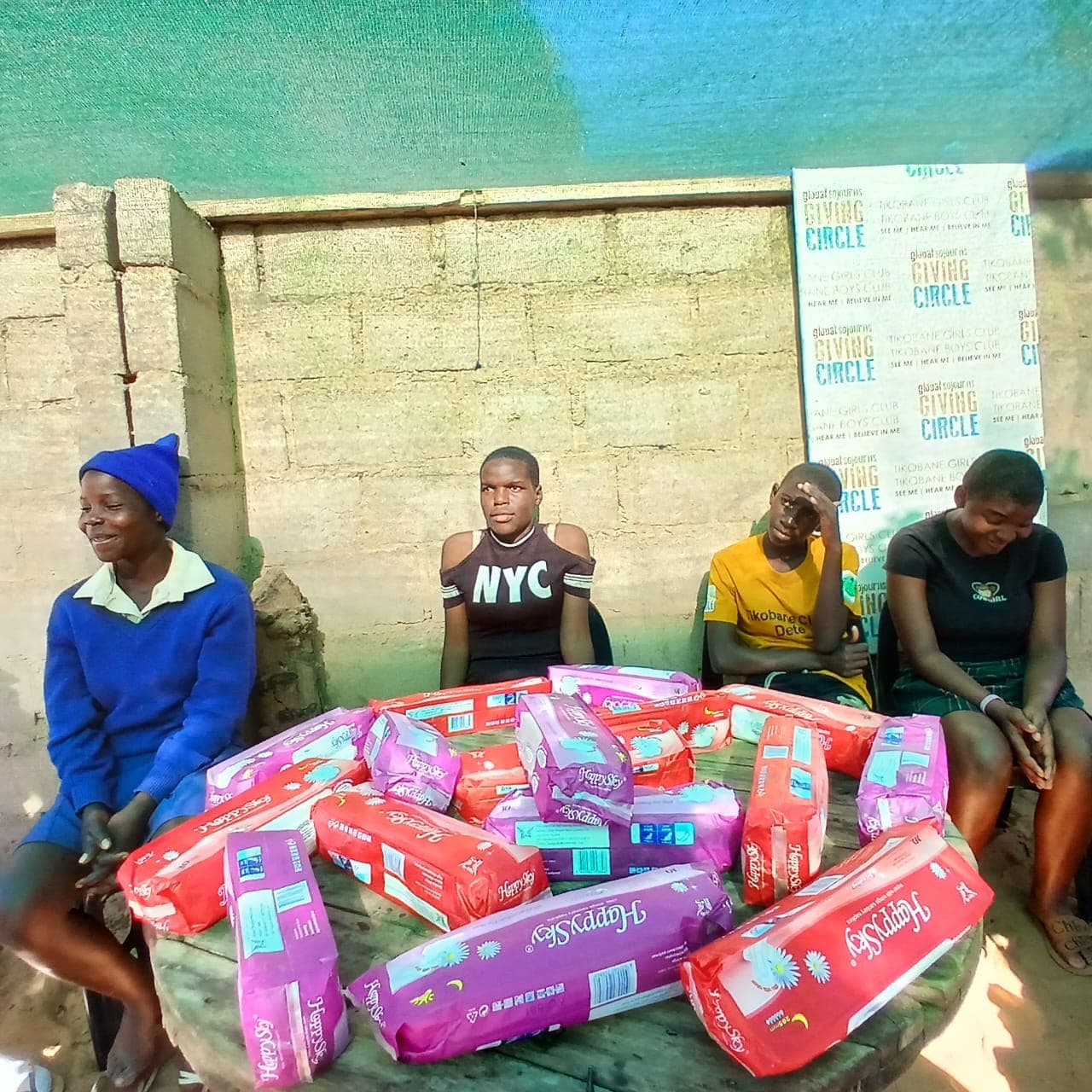 Community members seated beside packaged supplies