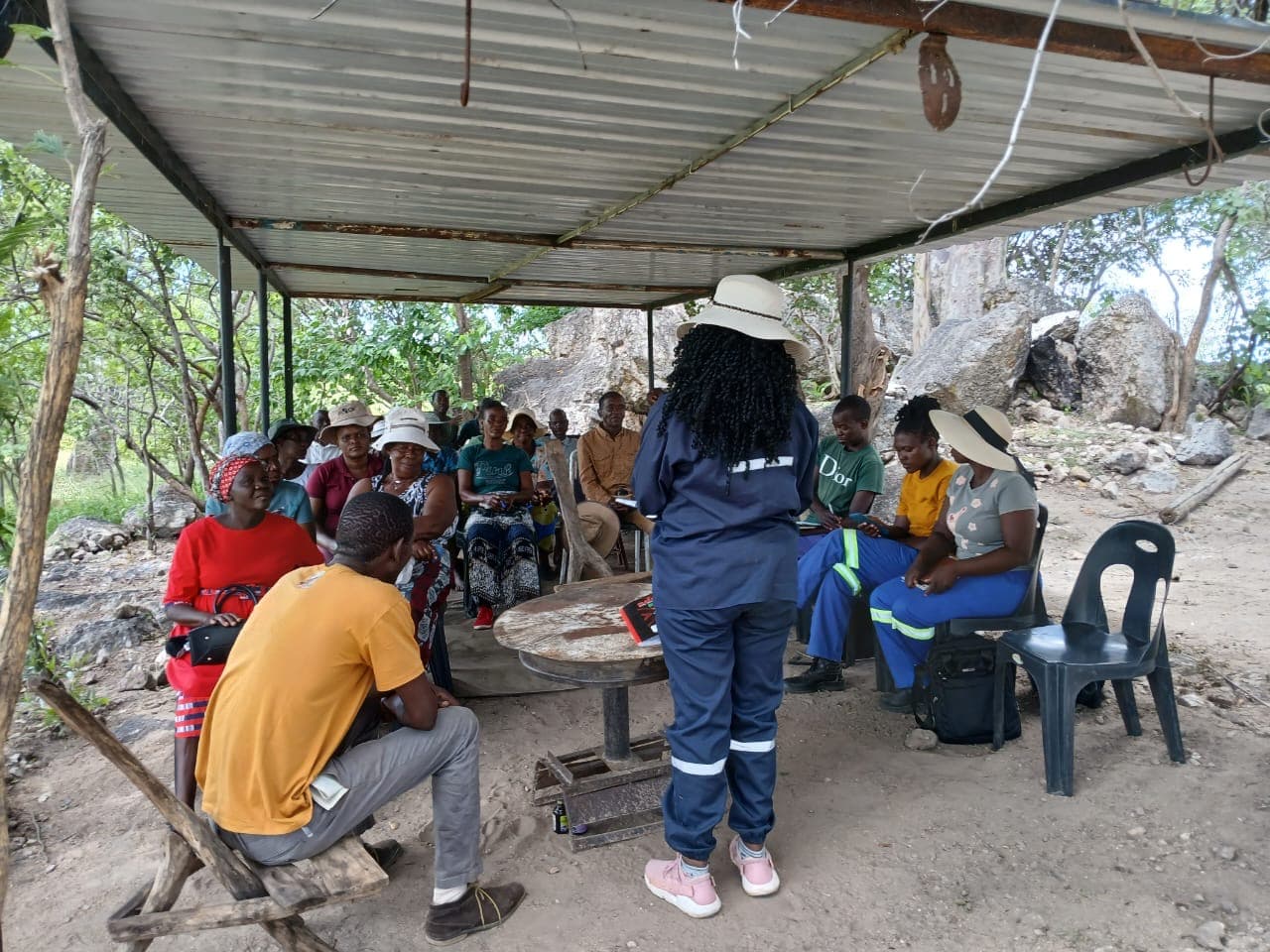 A facilitator addressing participants under a shelter