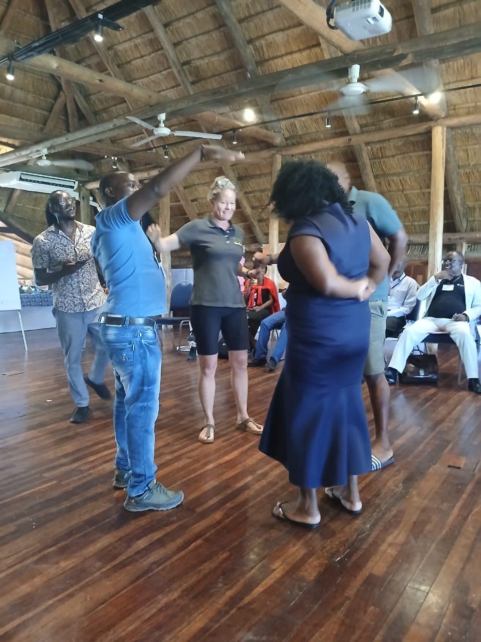 Participants talking in a thatched meeting space