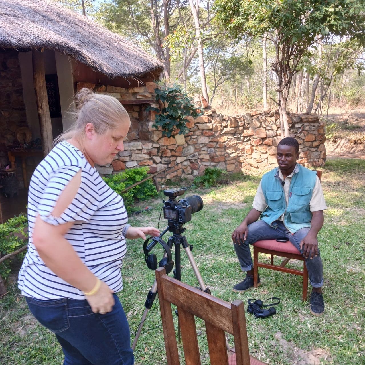 An outdoor interview being filmed beside a thatched building
